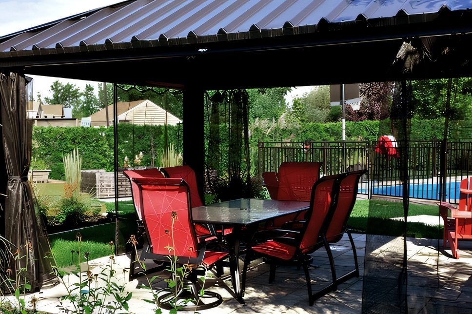 Table et chaises rouges sous une pergola, gazon et clôture de bois