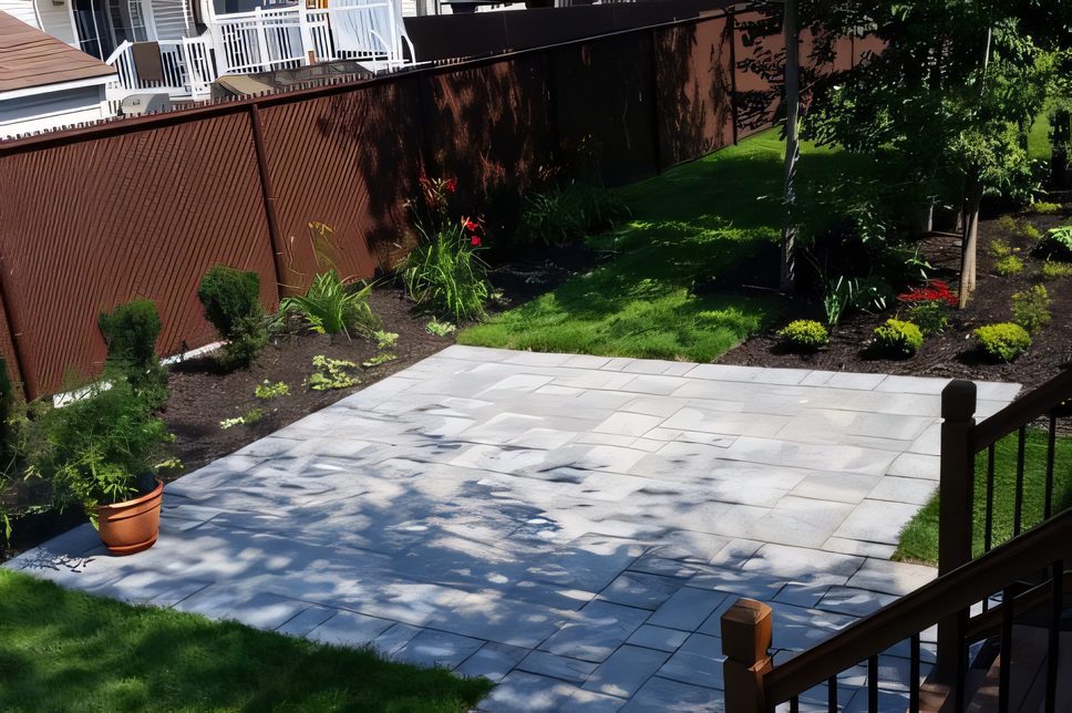 Cour arrière avec terrasse de pavé, gazon et clôture, arbres plantés