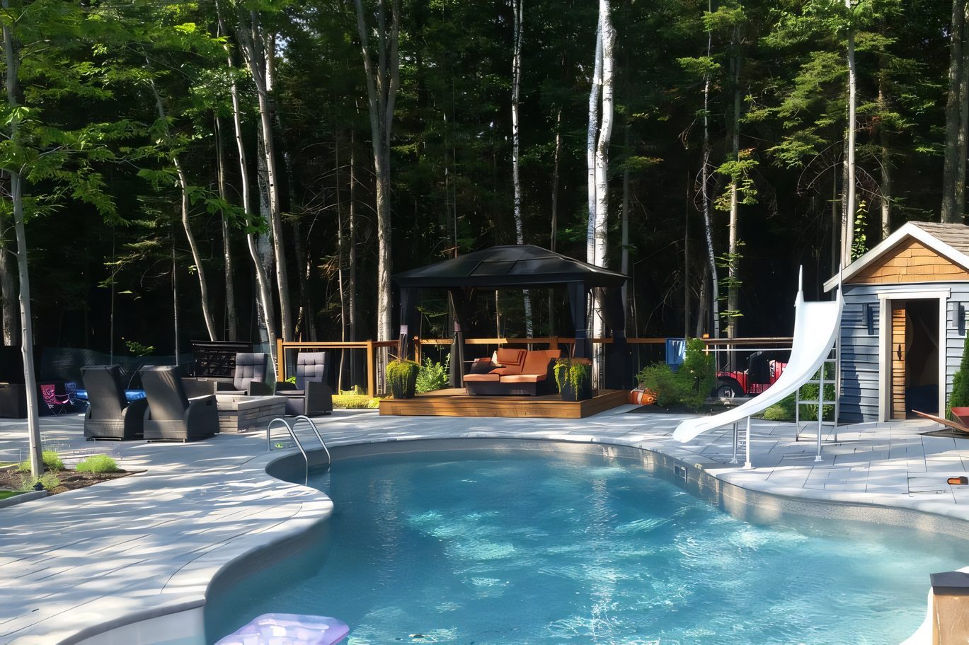 La même piscine finie, entourée de pavé de béton, la forêt derrière