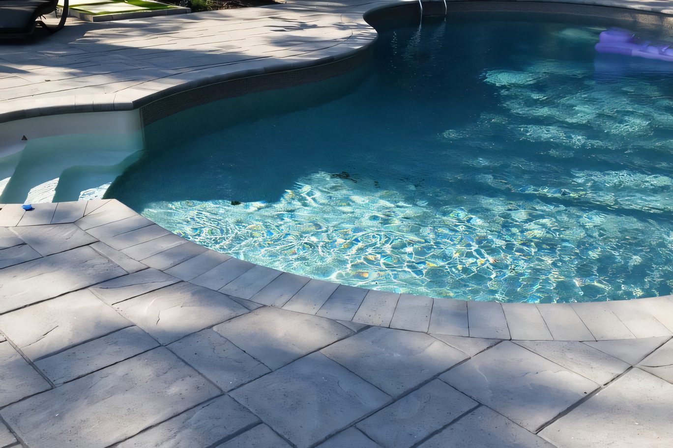 Le bord de la piscine : margelle et pavé de béton pâle