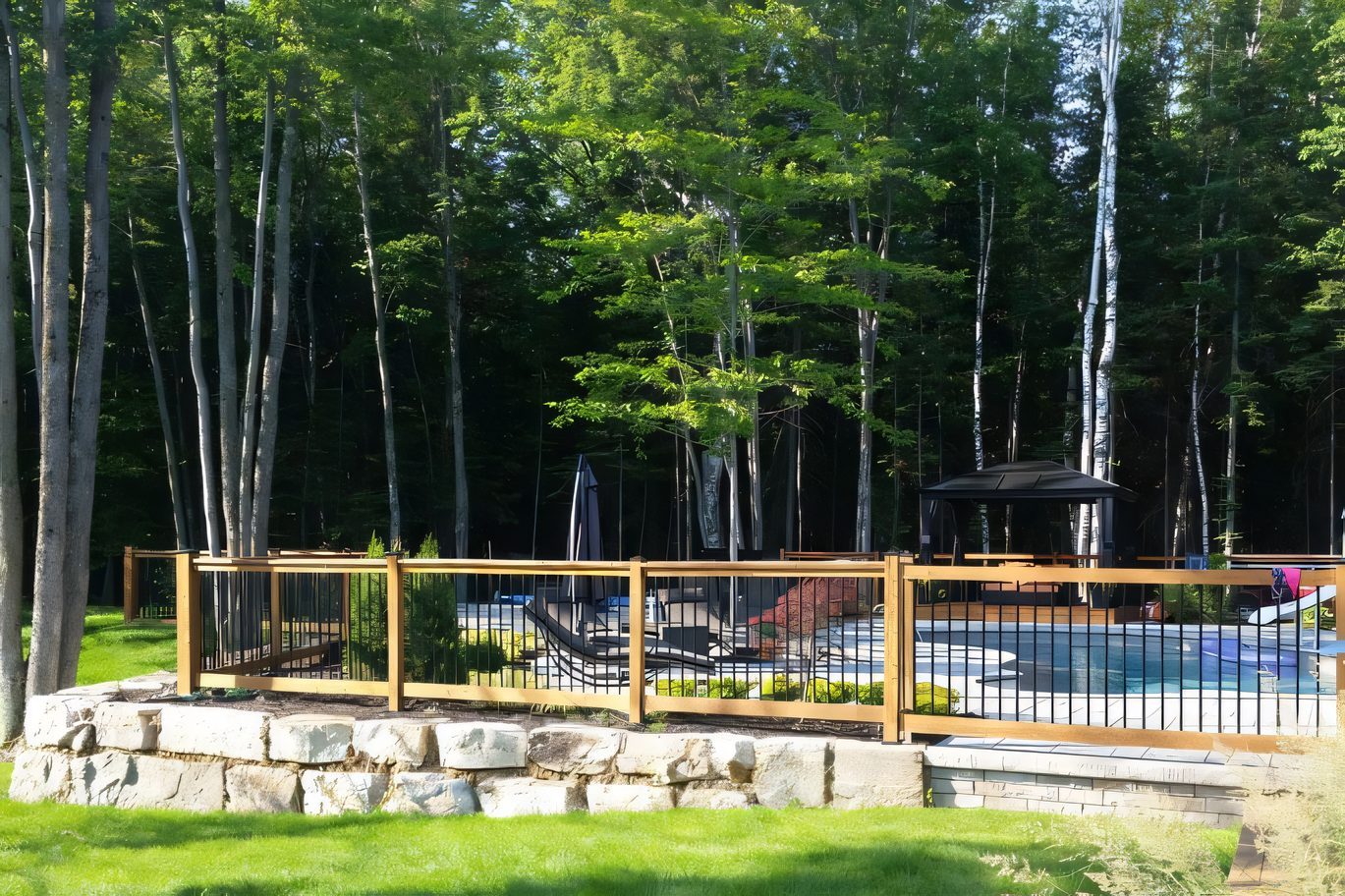 La piscine finie vue depuis la forêt, clôture et pavé