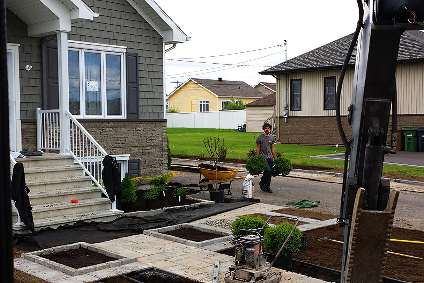 Un ouvrier pose des dalles de pavé entre deux maisons, l’espace est étroit